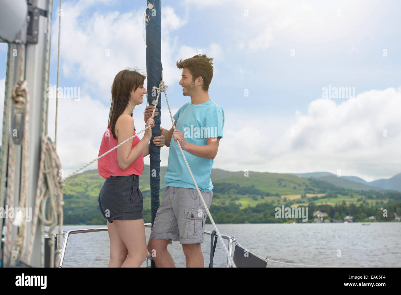 Young couple standing on bow of yacht sailing on lake under bright sunlight Stock Photo
