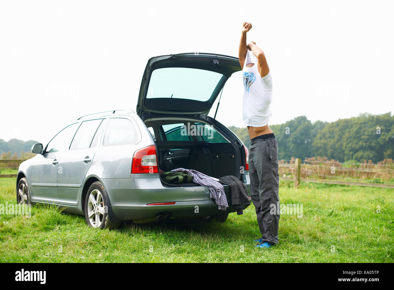 Man at rear of car changing clothes Stock Photo