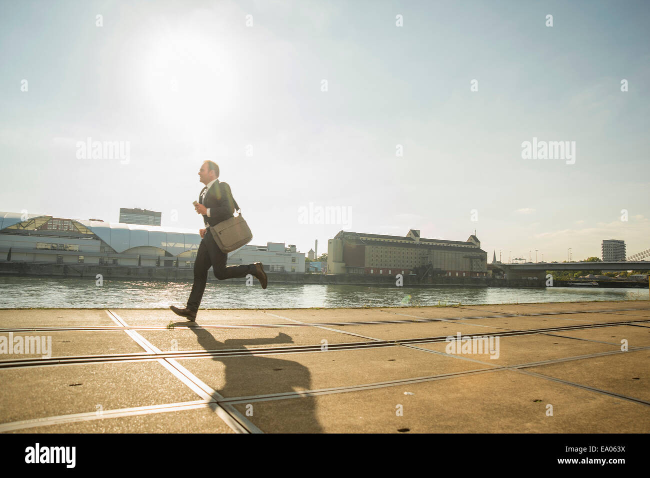 Businessman running along waterfront Stock Photo