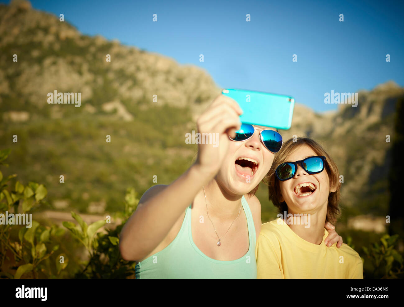 Sister and brother making faces for selfie on smartphone, Majorca, Spain Stock Photo