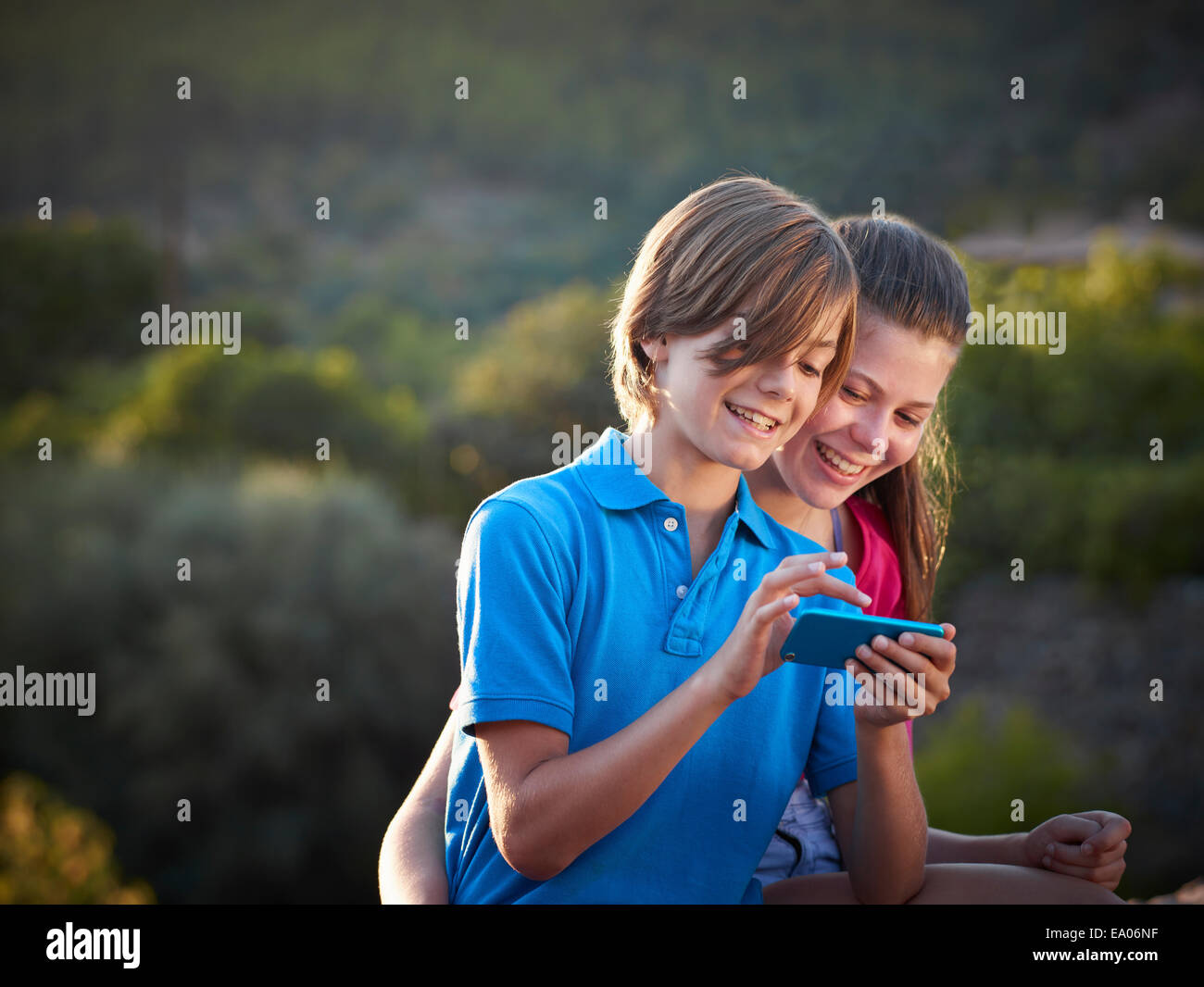 Brother and teenage sister using touchscreen on smartphone, Majorca, Spain Stock Photo
