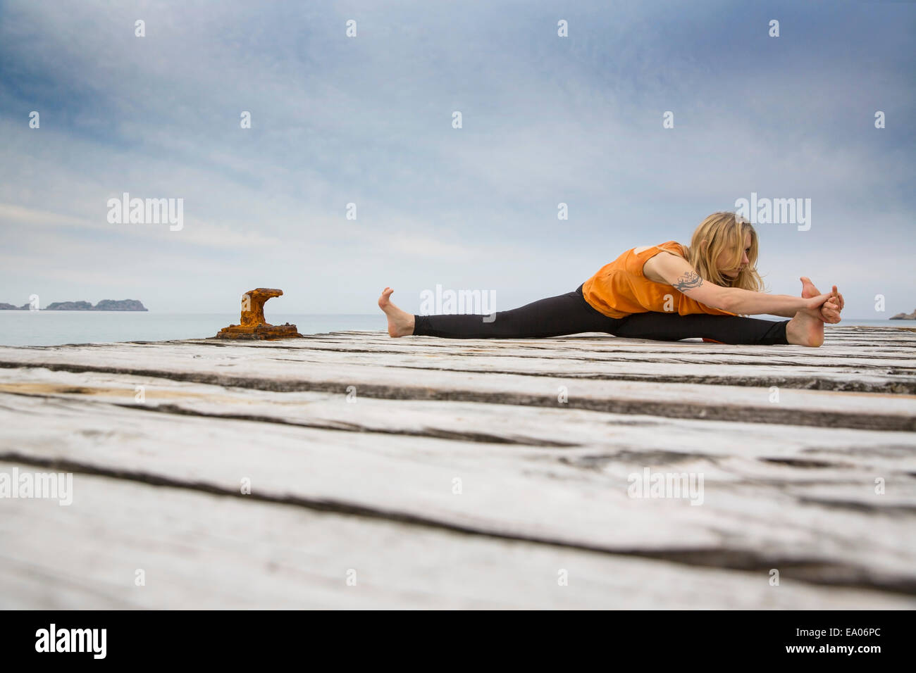 Mid adult woman practicing yoga on wooden sea pier Stock Photo