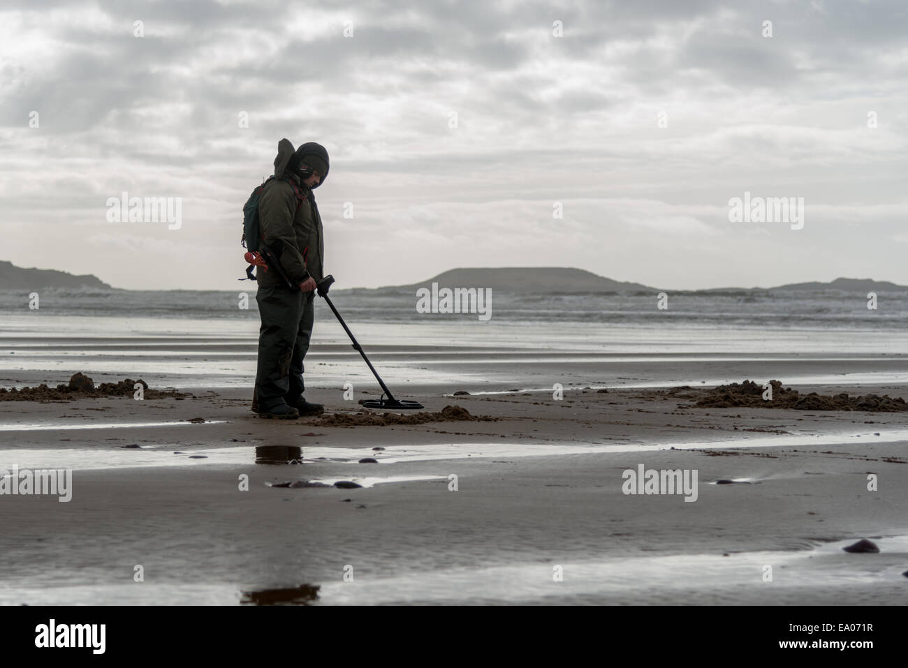 A man with metal detector searches on a beach near Llangennith, Gower Peninsula, south Walles. UK Stock Photo