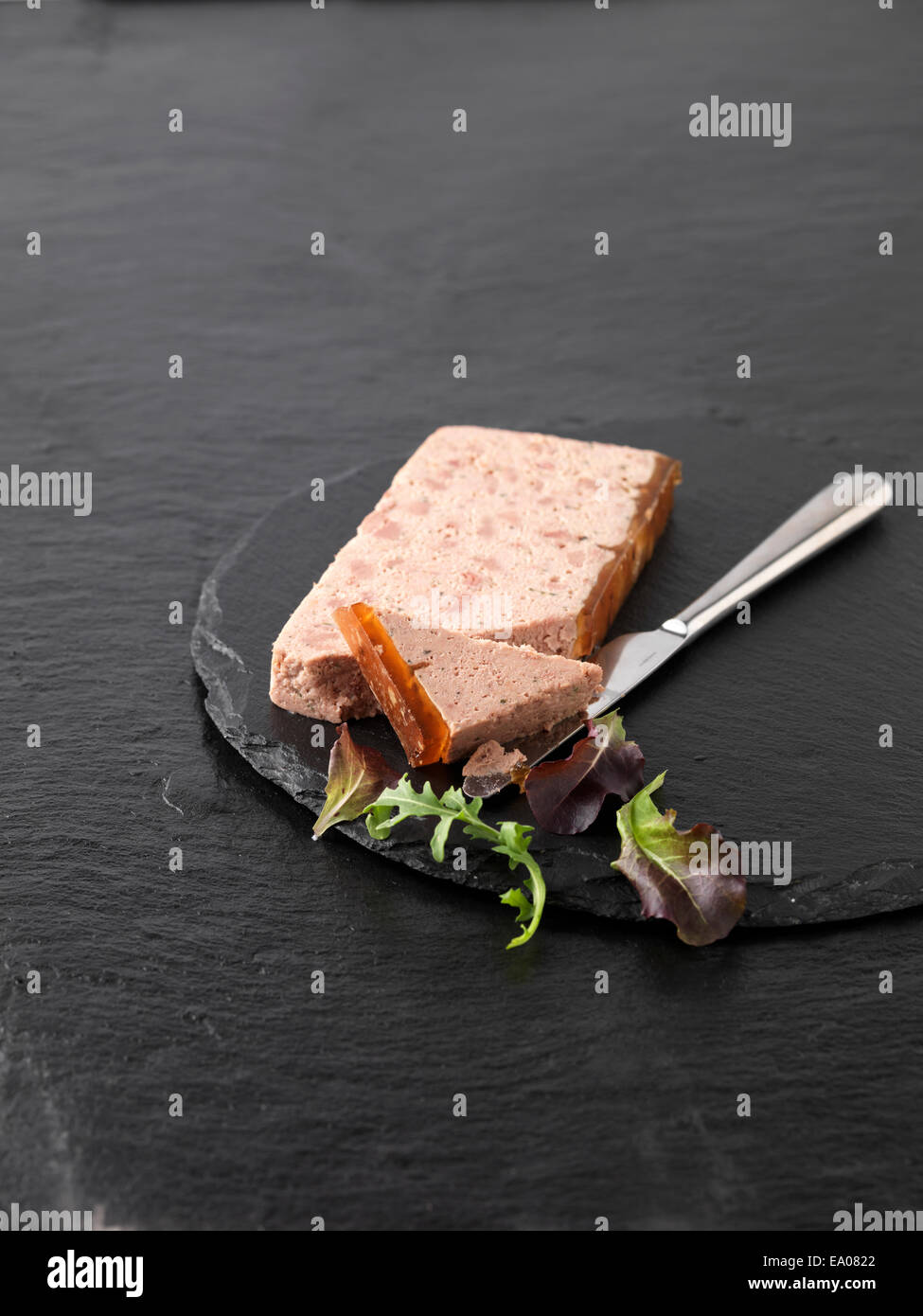 Christmas snack with Ardennes pate and rocket mixed salad leaves on slate cutting board Stock Photo