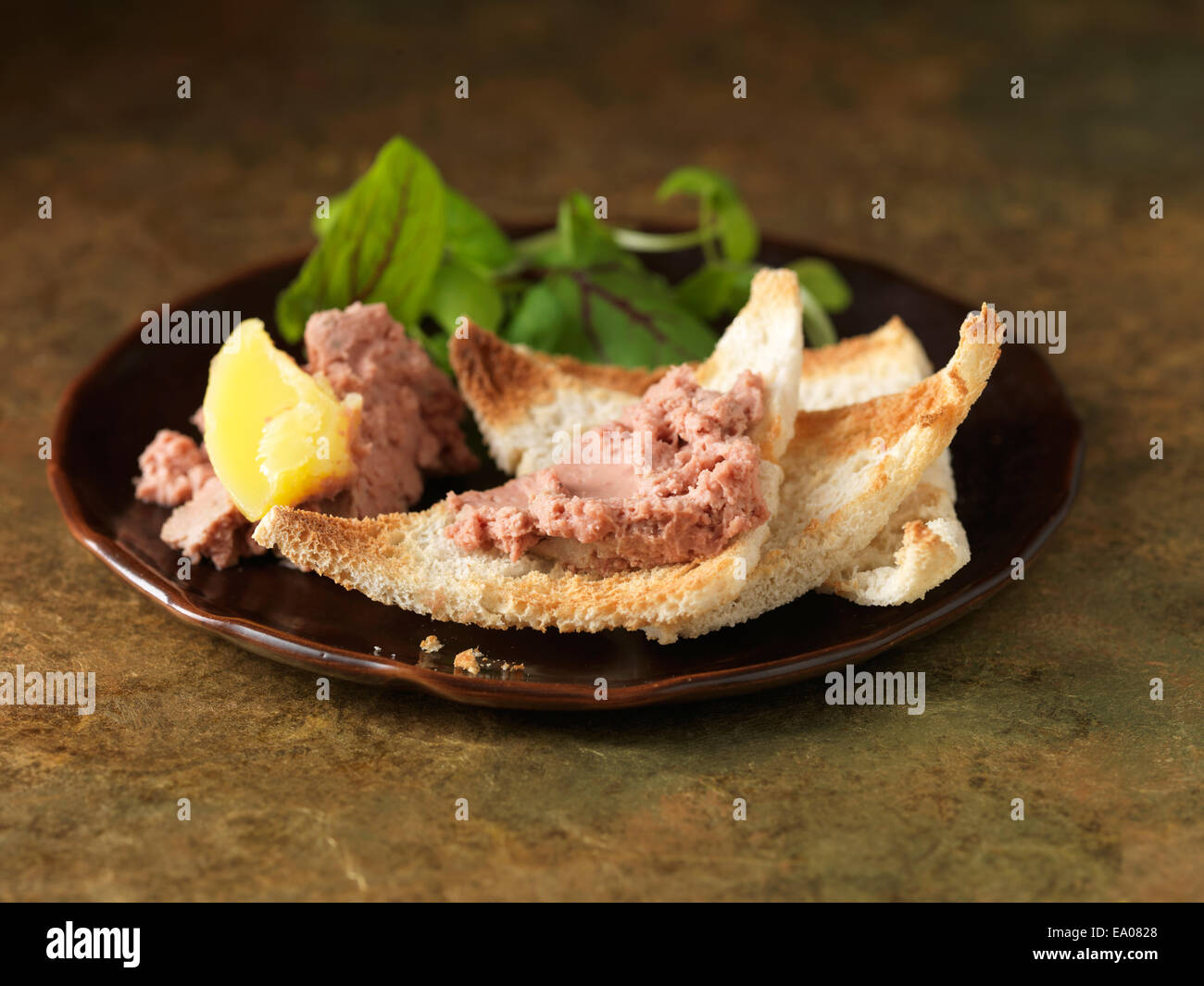 Christmas snack of chicken liver parfait with calvados. Green salad leaves and white bread toasted crumbs Stock Photo
