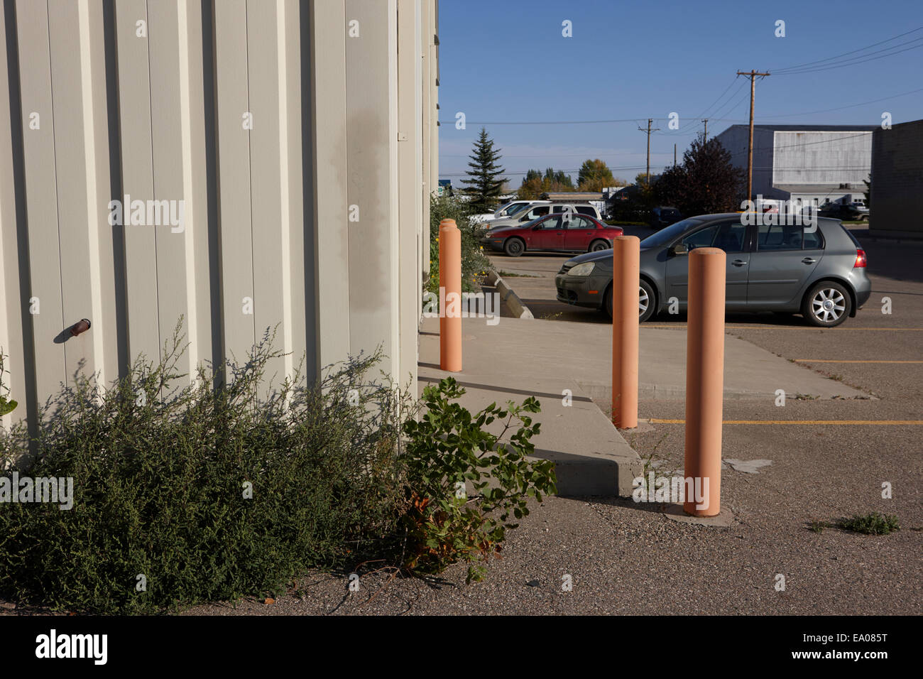 protective steel bollards in a parking lot outside an industrial building entrance Saskatchewan Canada Stock Photo