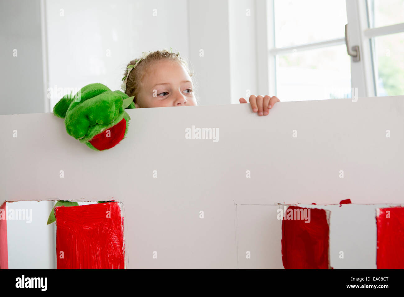 Girl peering over toy theatre with puppet Stock Photo