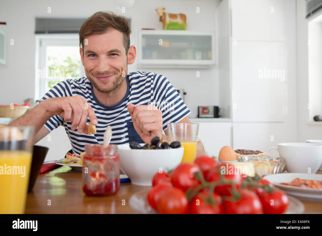 Mid adult man eating at kitchen table Stock Photo