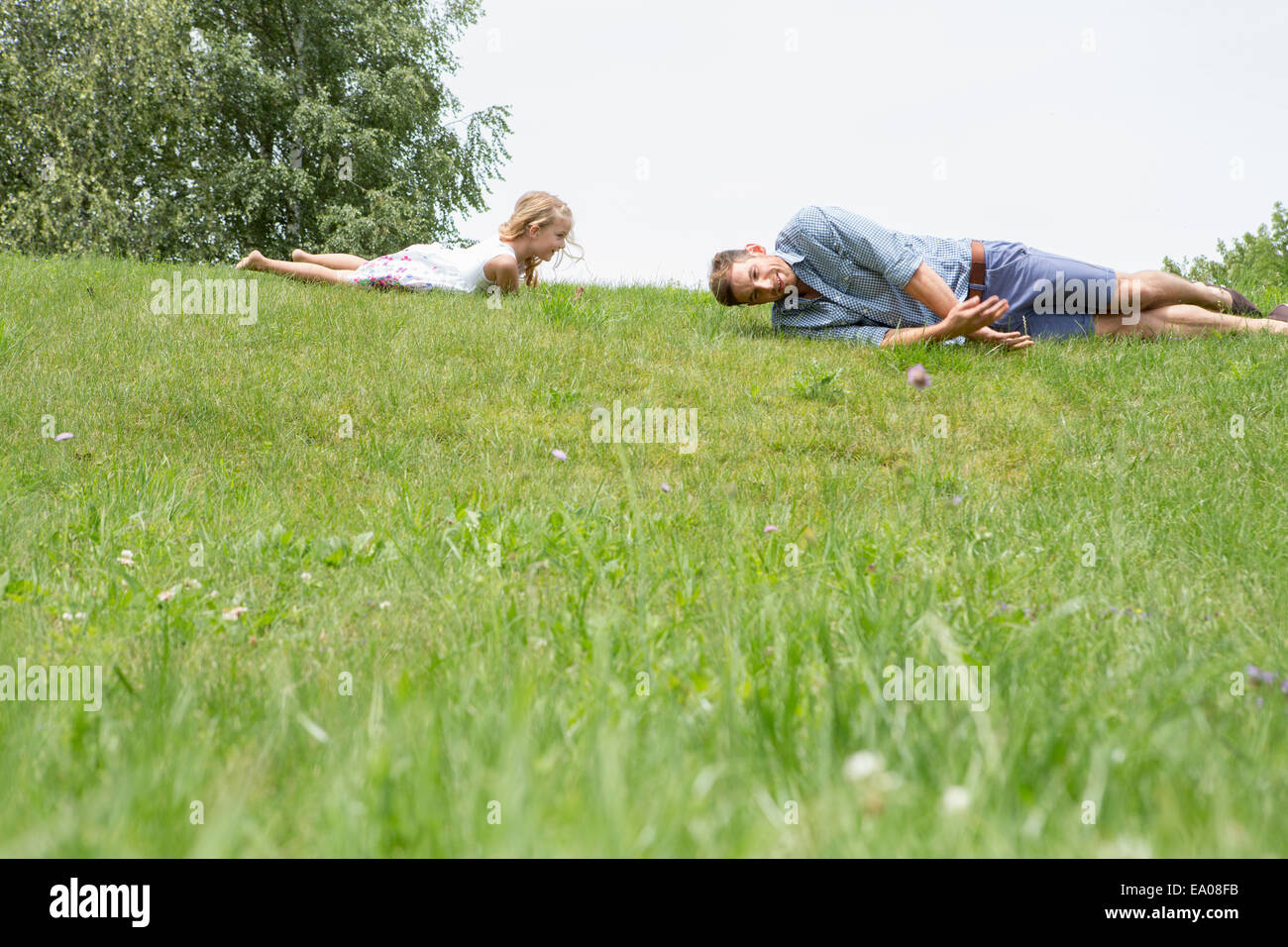 Father and daughter rolling downhill Stock Photo