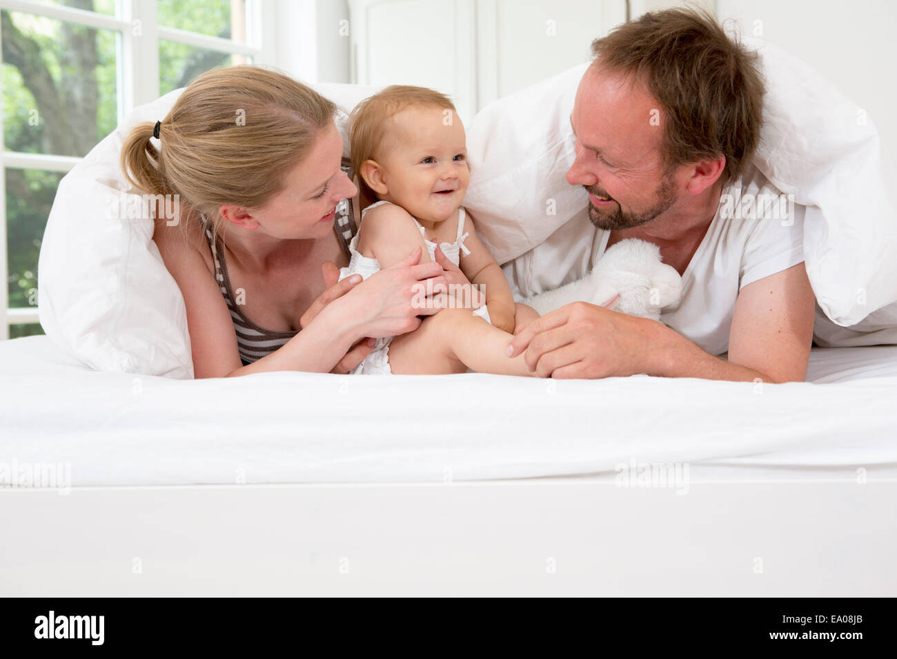 Parents playing with baby daughter under duvet Stock Photo Alamy