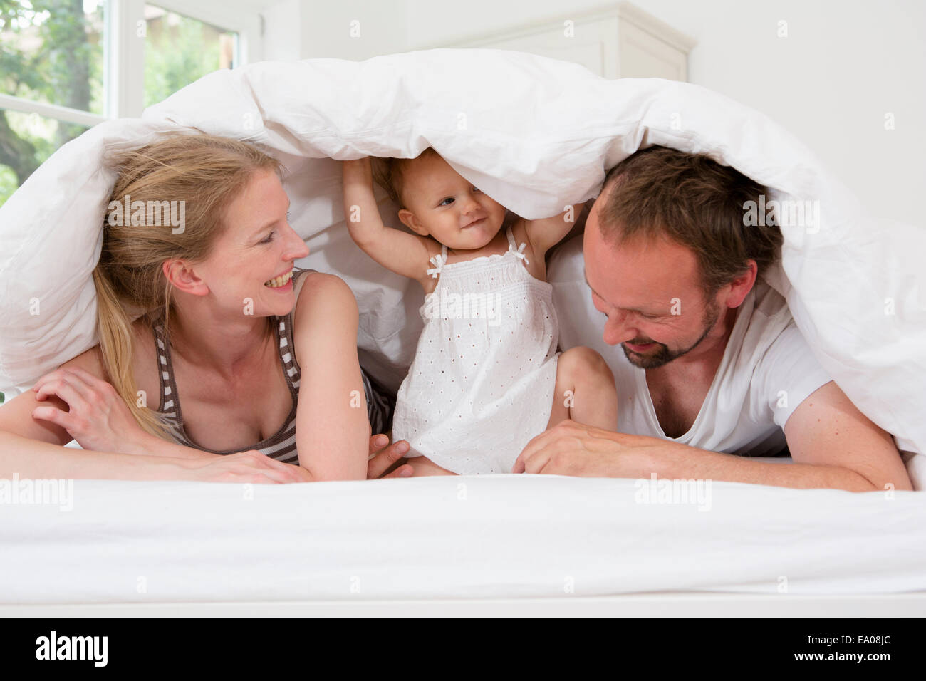 Parents playing with baby daughter under duvet Stock Photo Alamy