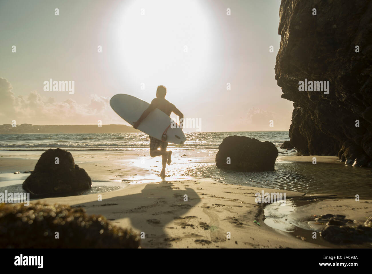 Mature man running towards sea, holding surf board Stock Photo