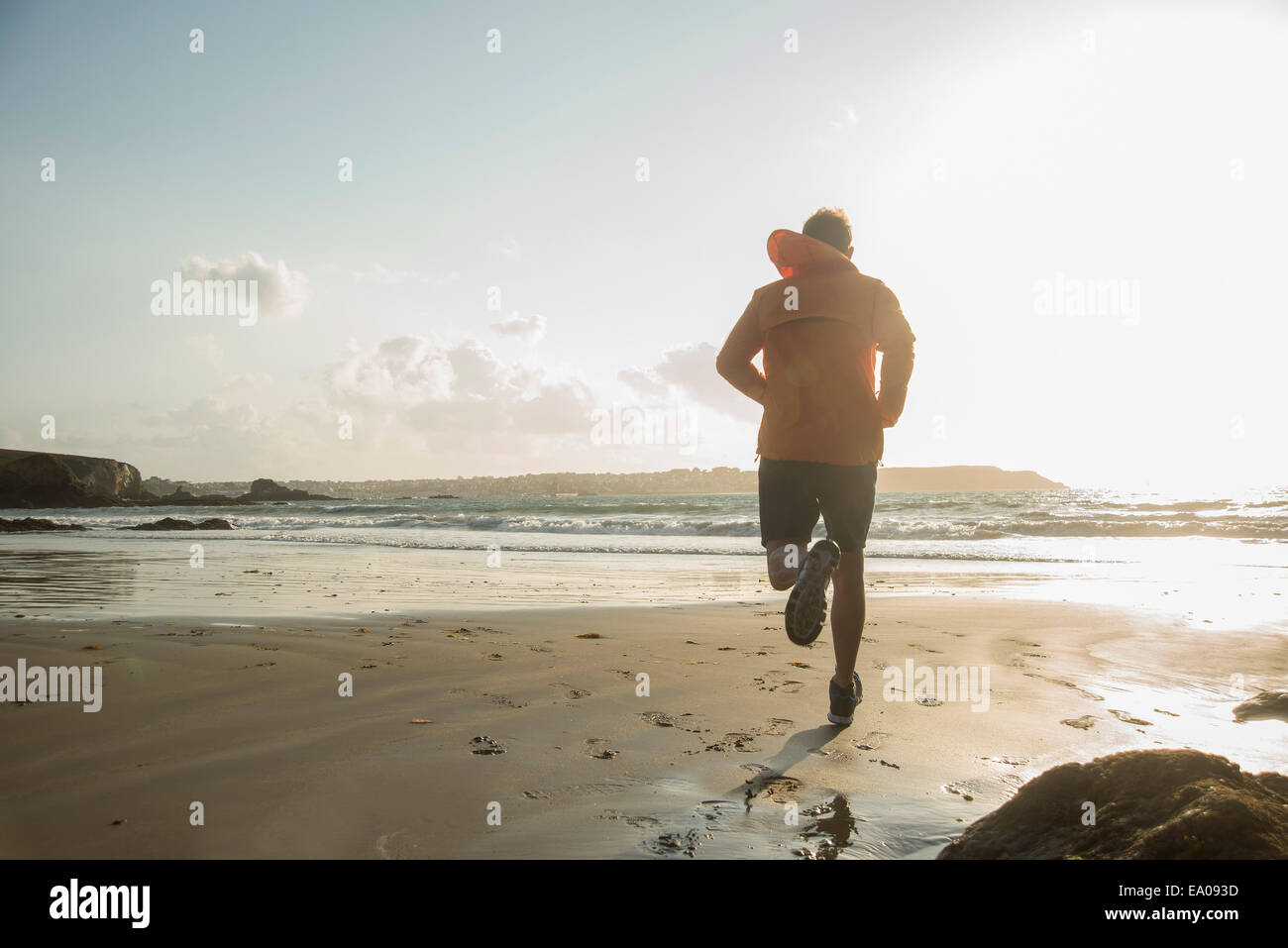 Mature man running on sand, along coastline Stock Photo