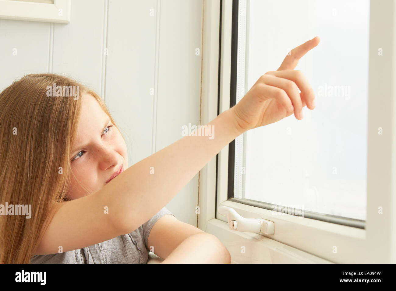 Girl pointing out of holiday apartment window Stock Photo