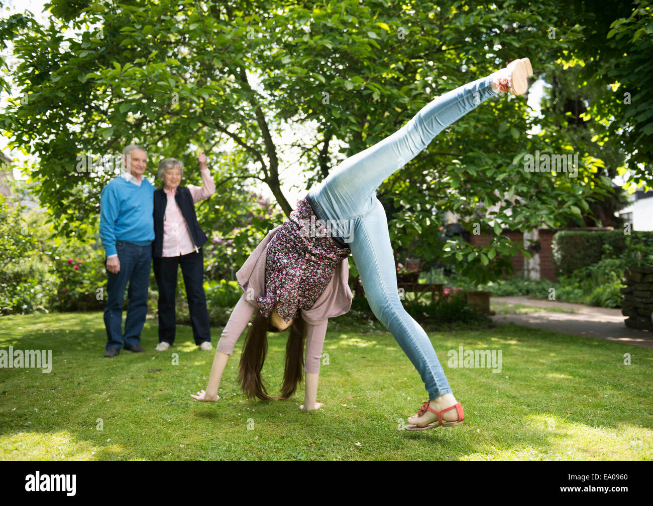 Grandparents and granddaughter doing acrobatics in garden Stock Photo