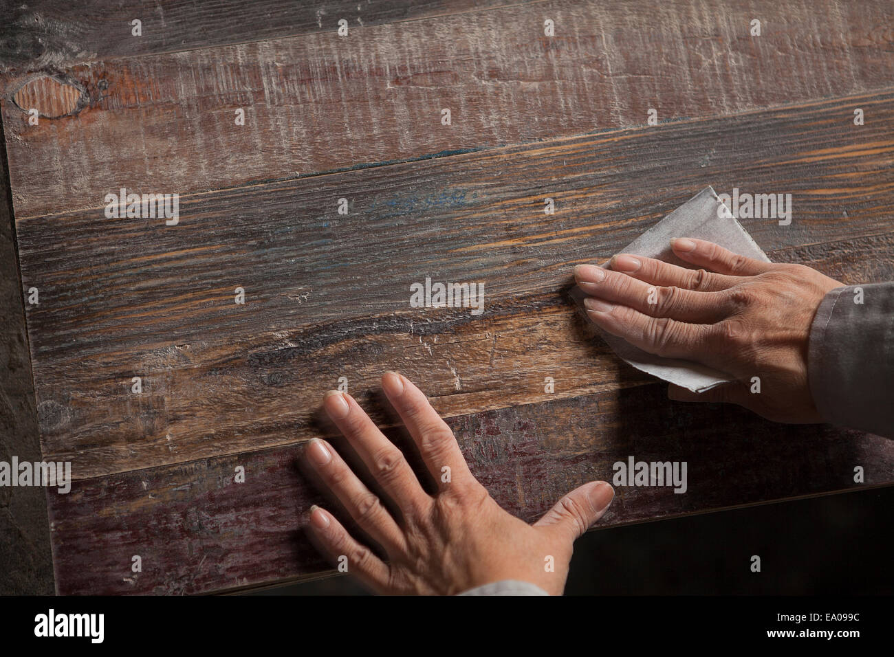Carpenter smoothing surface of wood plank with sandpaper in factory, Jiangsu, China Stock Photo