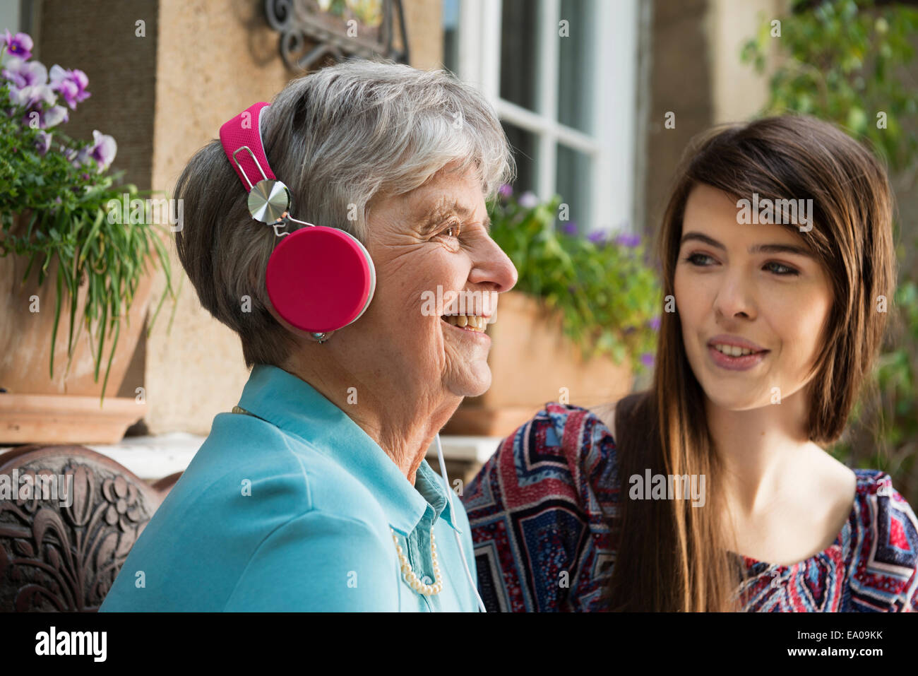 Senior woman wearing headphones with granddaughter Stock Photo