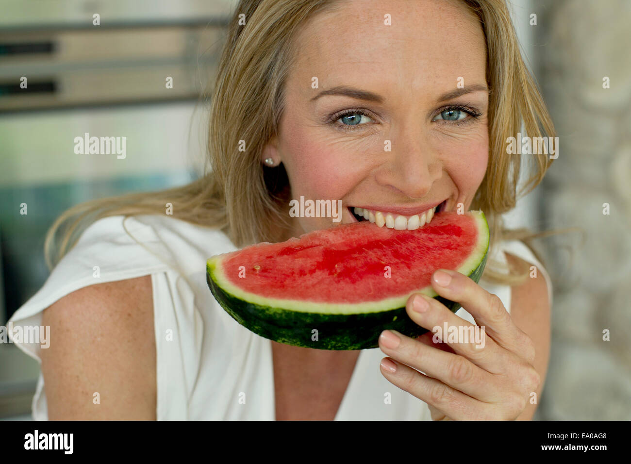 Mature woman biting watermelon Stock Photo