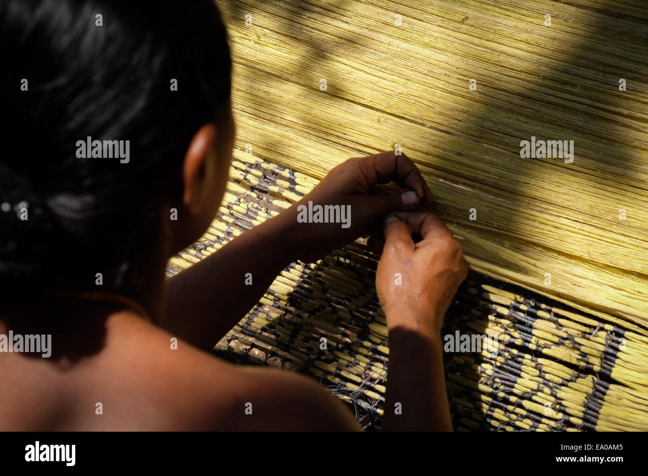 A woman preparing patterns before weaving at a workshop in Lamagute village, Lembata Island, Indonesia. Stock Photo