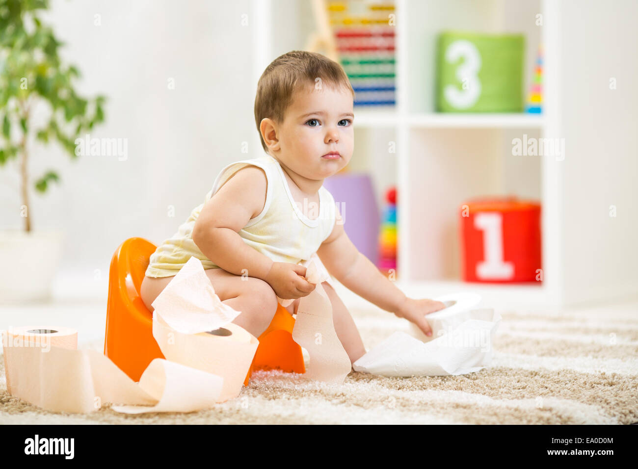 kid boy sitting on chamber pot with toilet paper Stock Photo