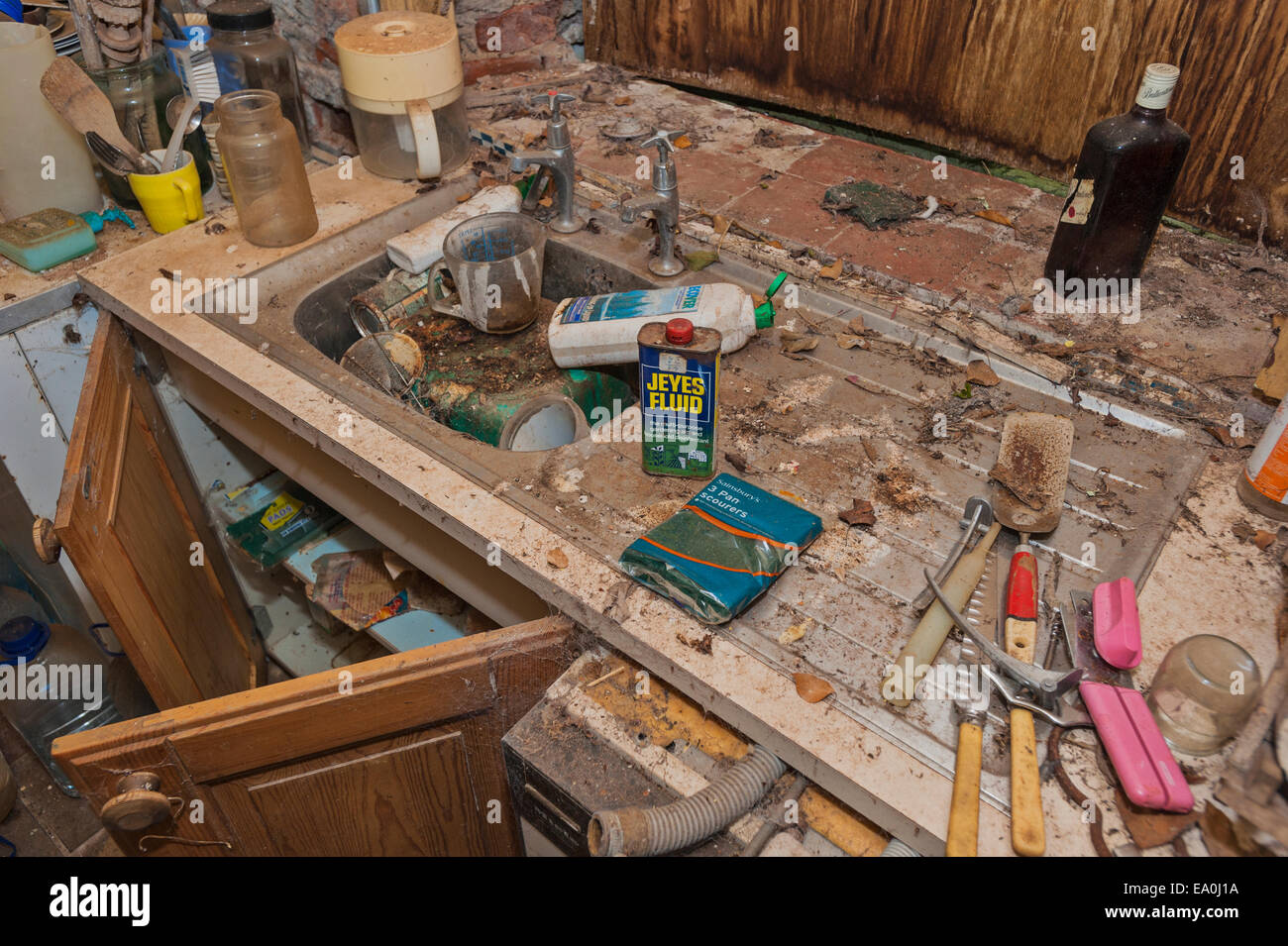 The sink and worktop in the kitchen of a derelict and abandoned house Stock Photo