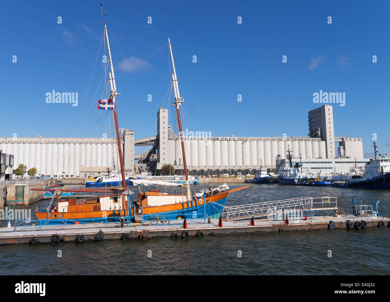 Old wooden sailing boat moored in front of the Bunge grain silos, Quebec City, Quebec, Canada Stock Photo