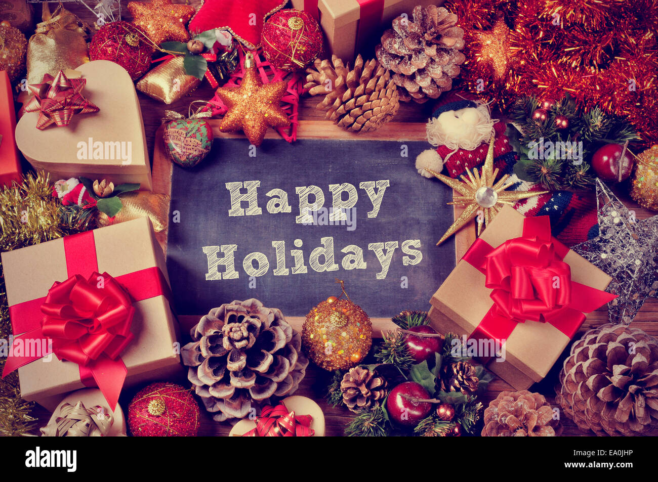 a pile of gifts and christmas ornaments, such as christmas balls or stars, with a chalkboard in the center with the text happy h Stock Photo