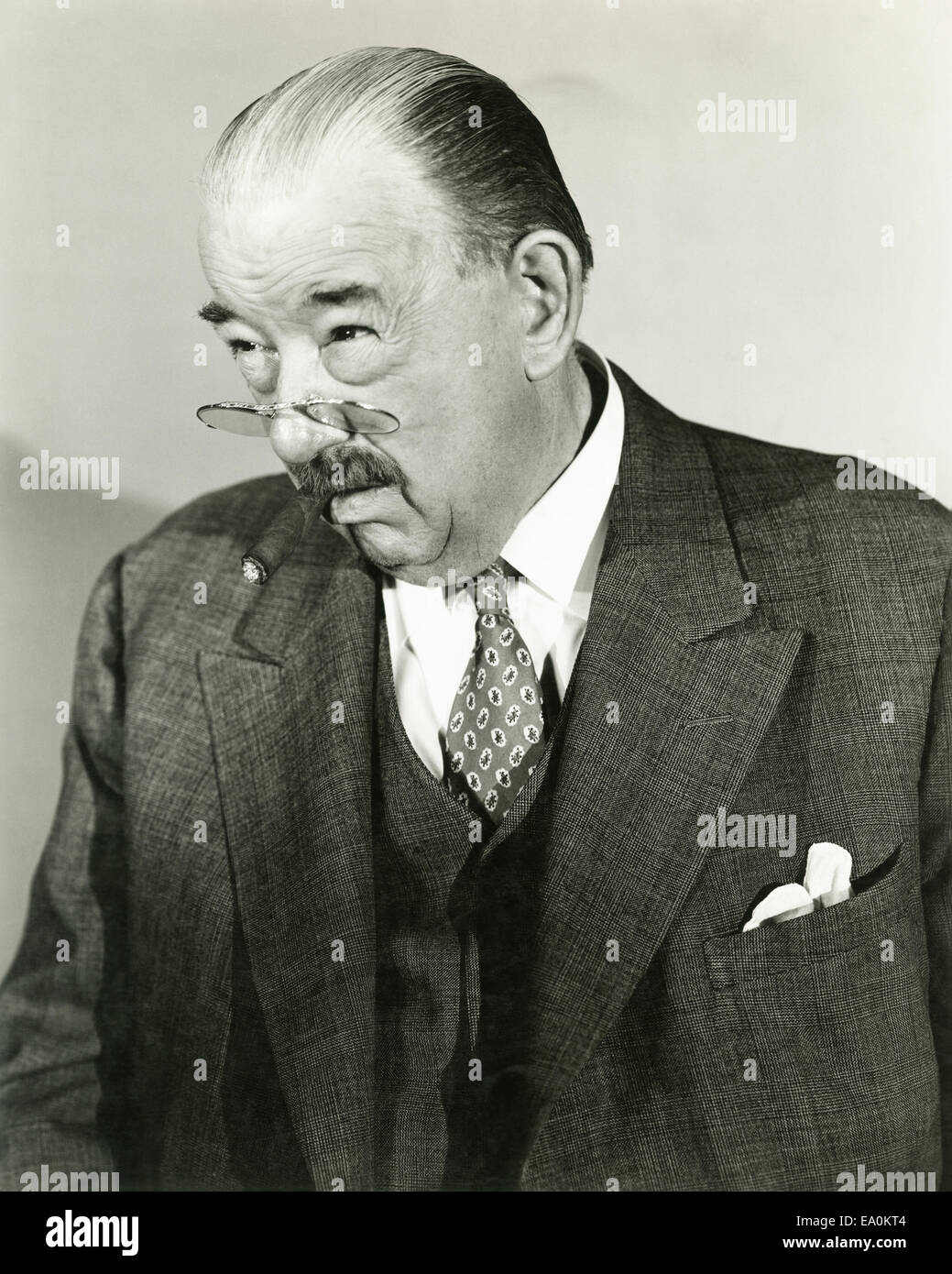 A man peers over the top of his pince-nez Stock Photo