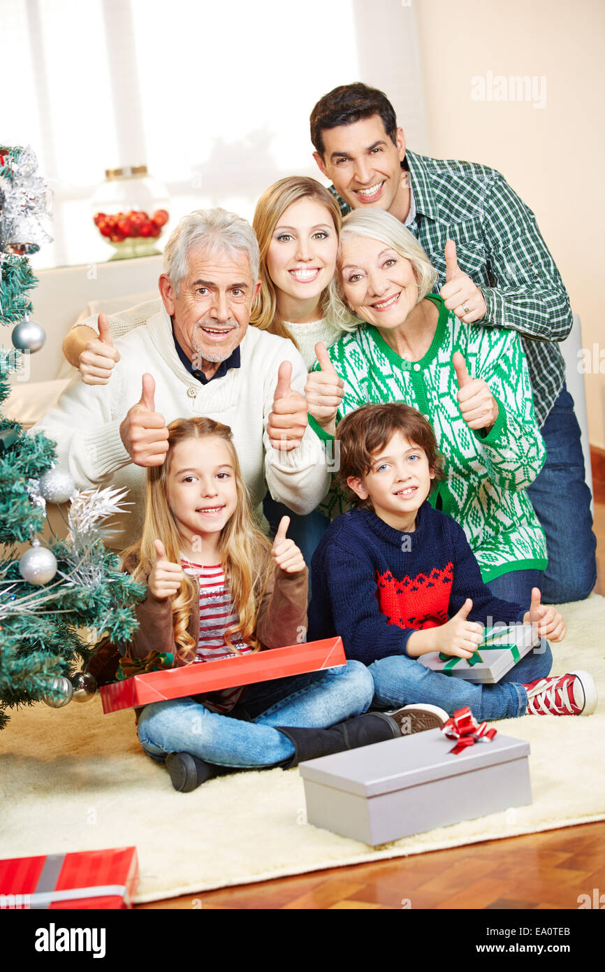 Happy family at christmas with gifts holding thumbs up Stock Photo