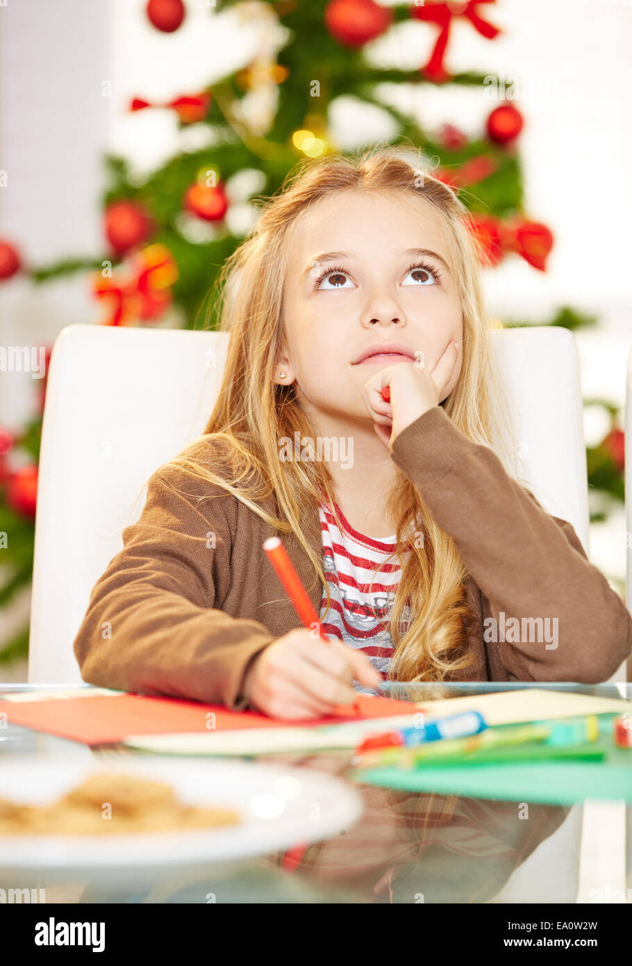 Pensive child writing wishlist to Santa Claus for christmas Stock Photo