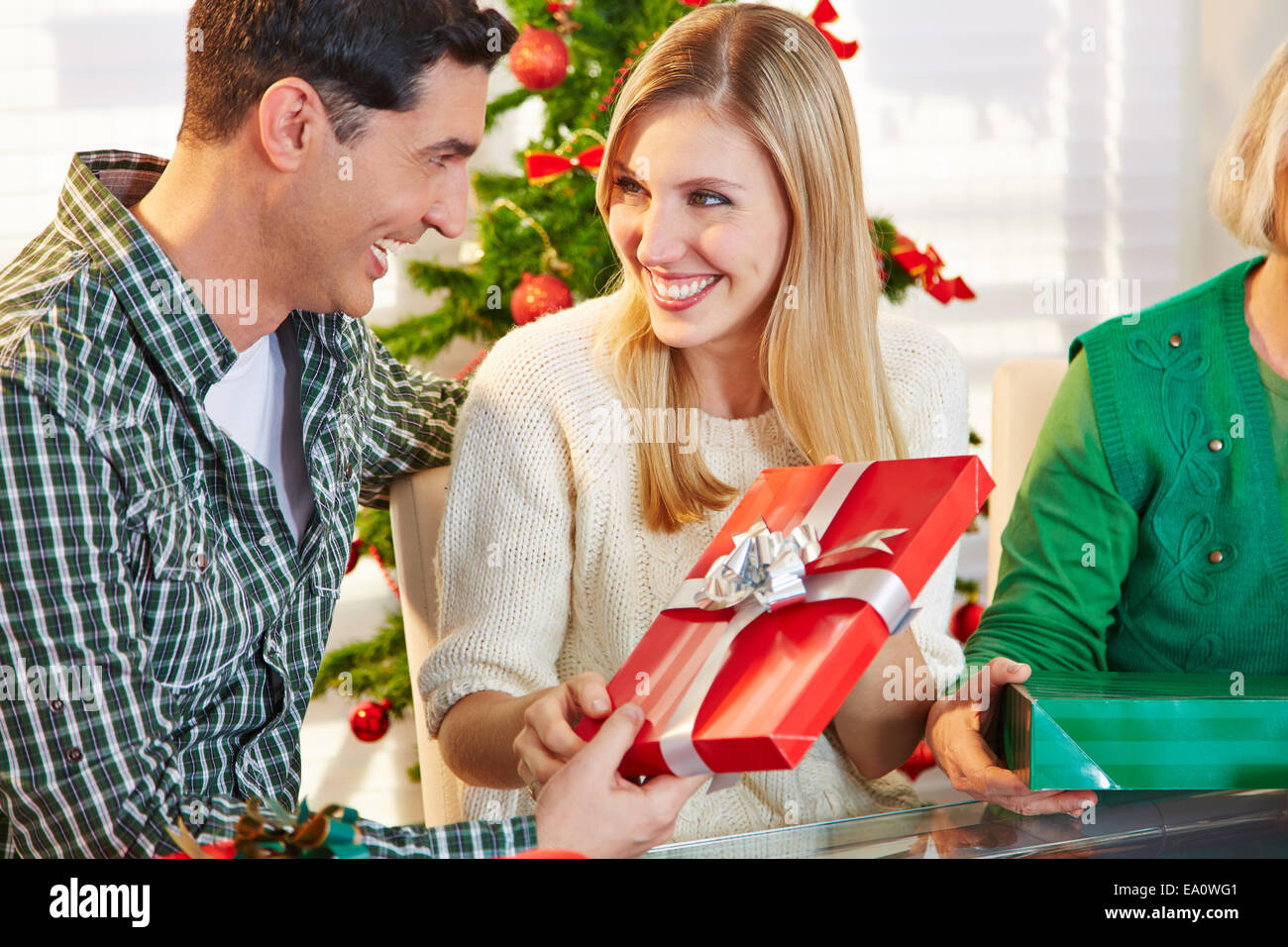 Happy smiling couple exchanging gifts at christmas eve Stock Photo