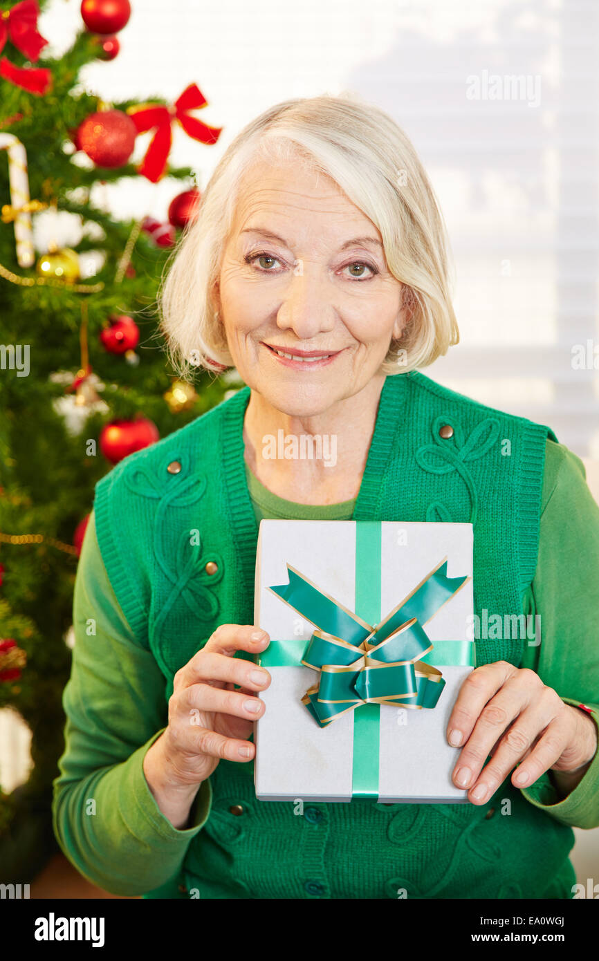 Happy senior woman holding gift with ribbon at christmas Stock Photo