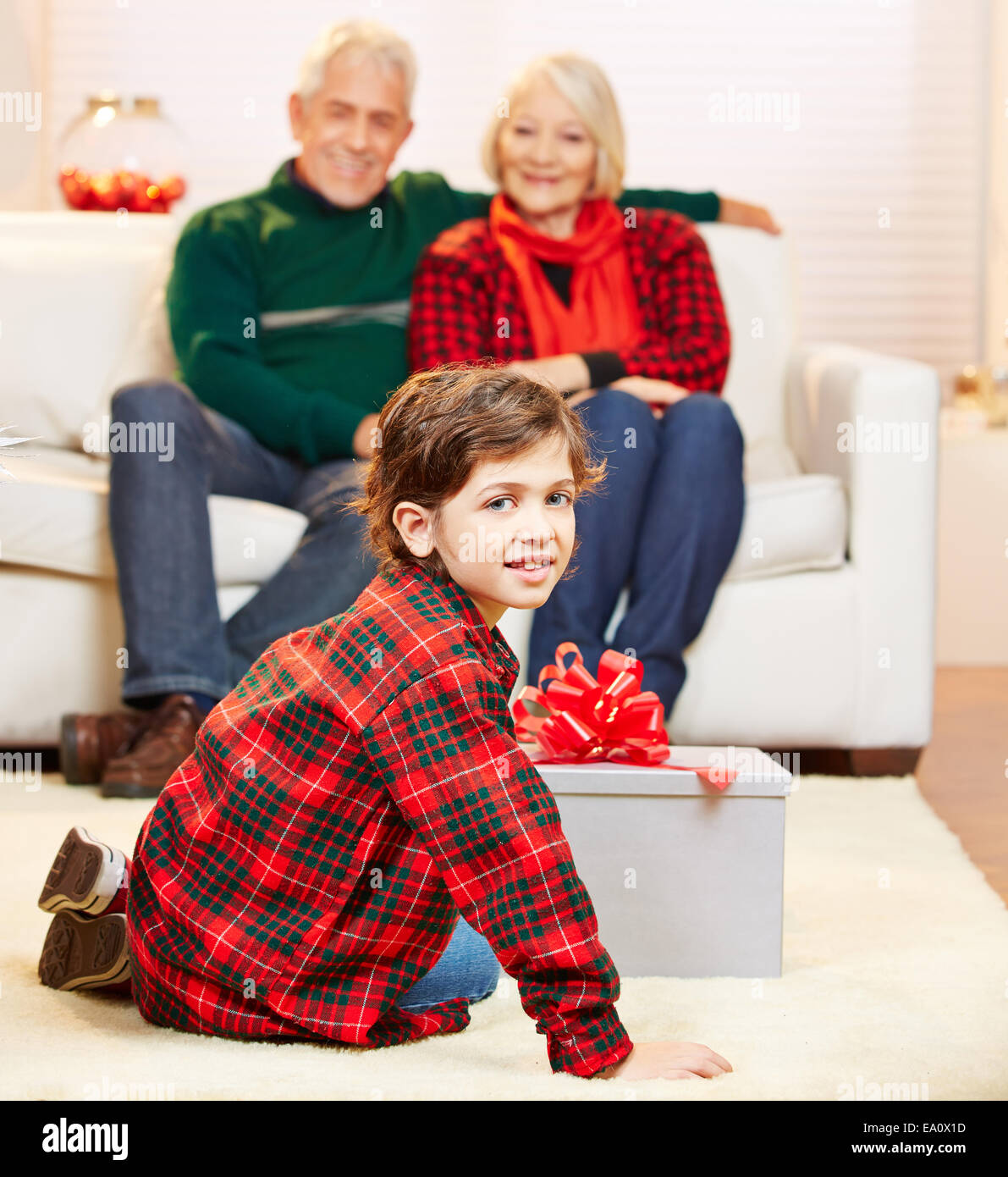 Grandchild opening gift from grandparents at christmas Stock Photo