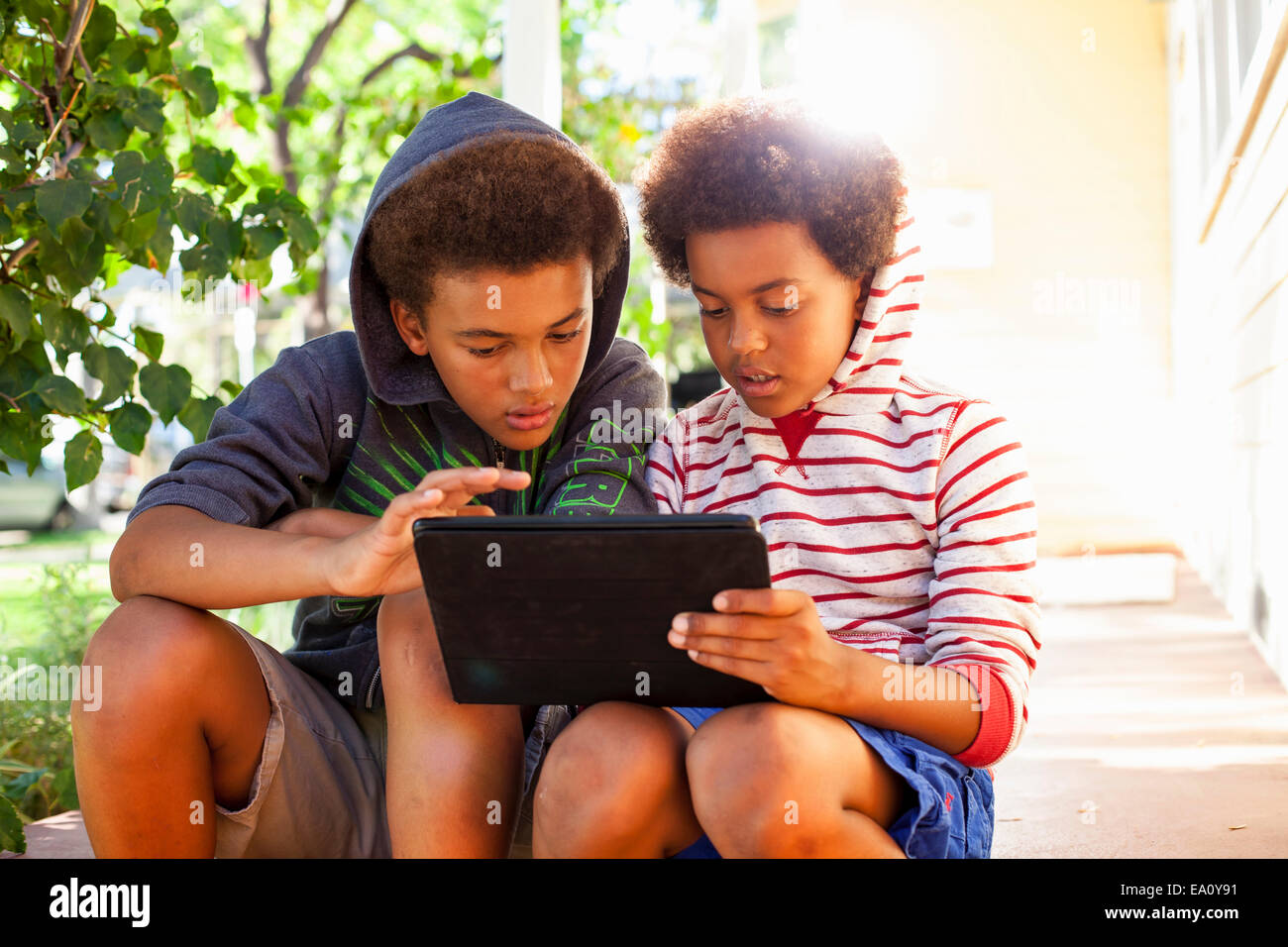 Two brothers using touchscreen on digital tablet in garden Stock Photo