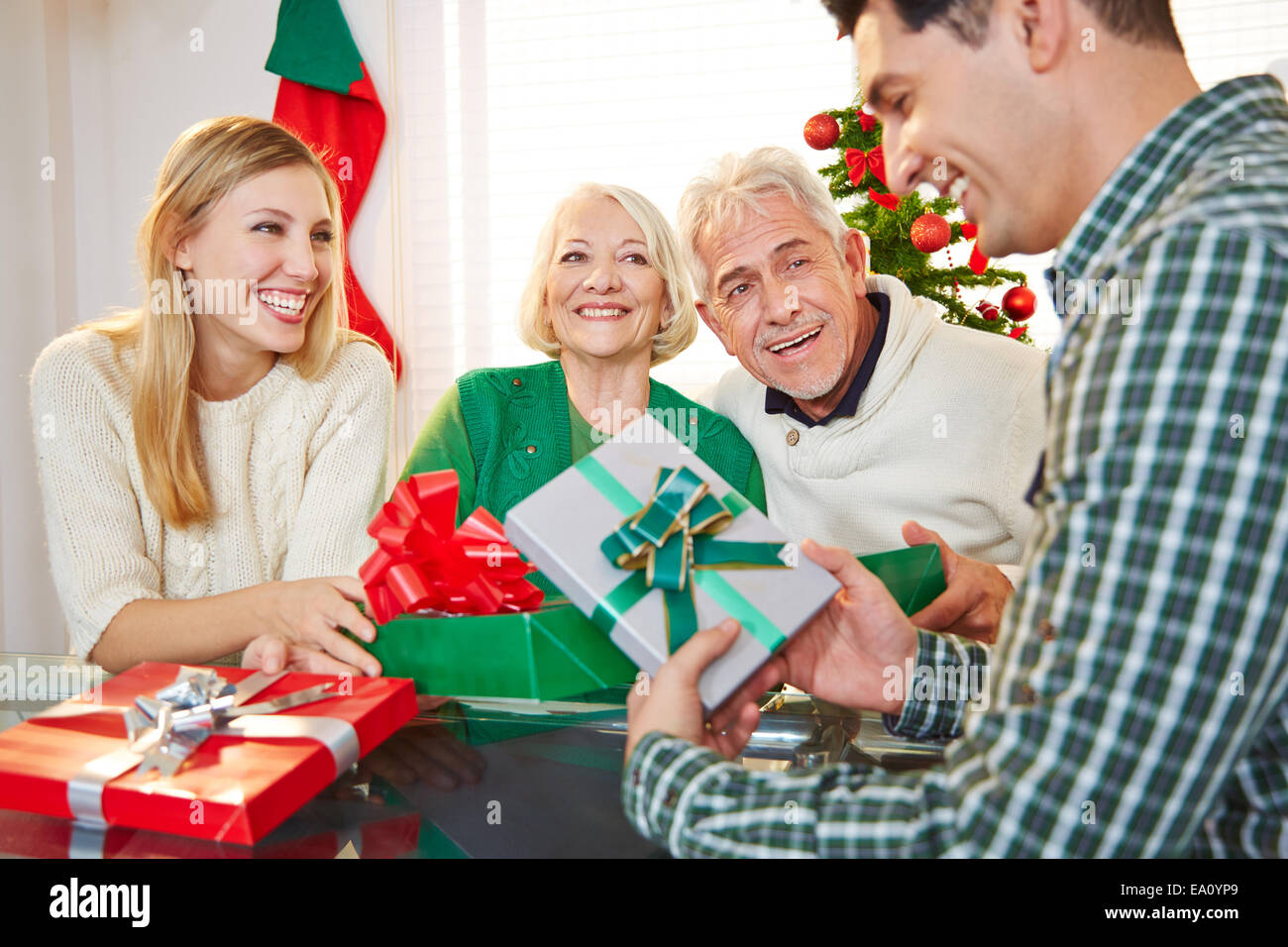Happy couple celebrating christmas eve with gifts and seniors Stock Photo