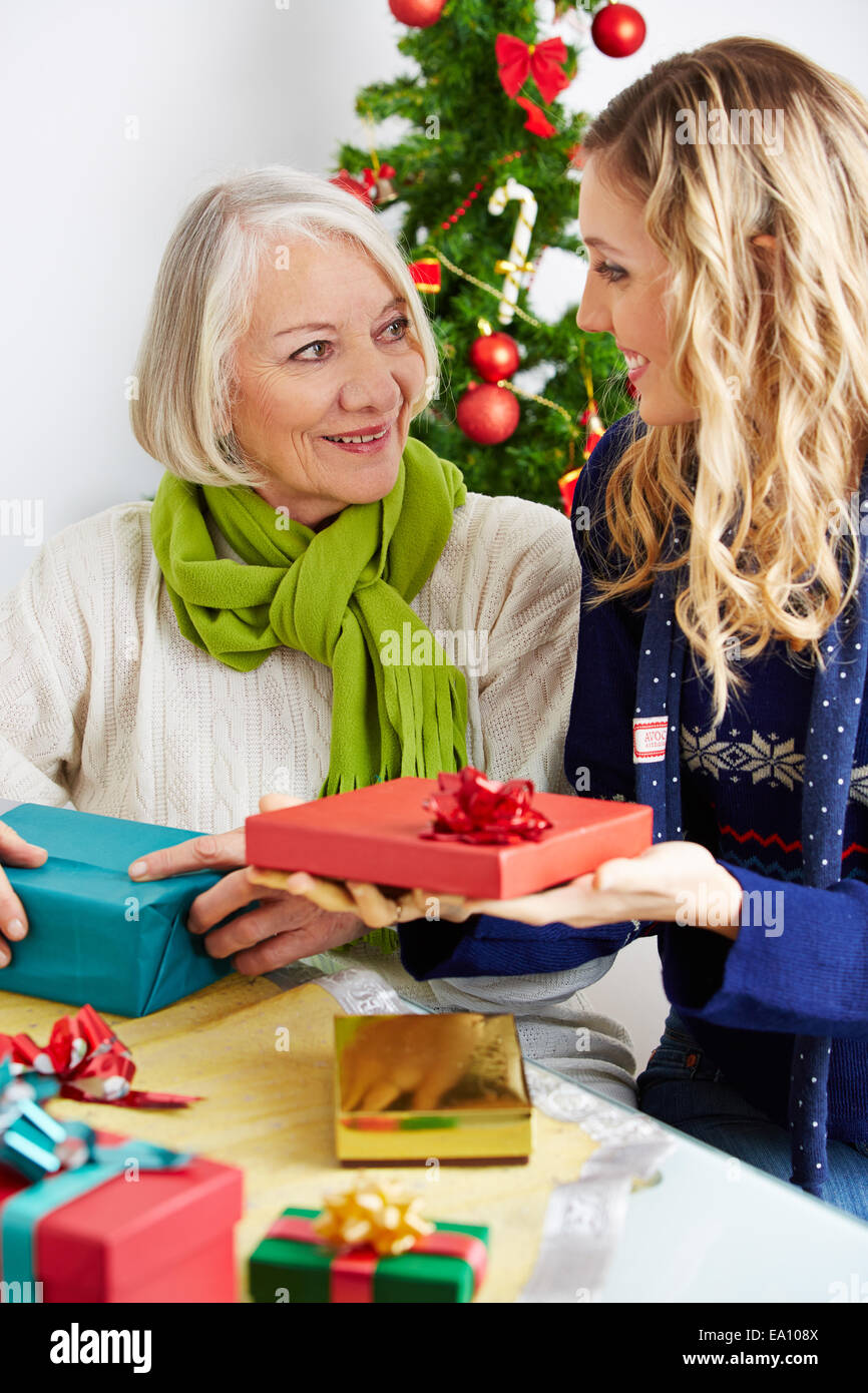 Smiling woman giving senior citizen a gift for christmas Stock Photo