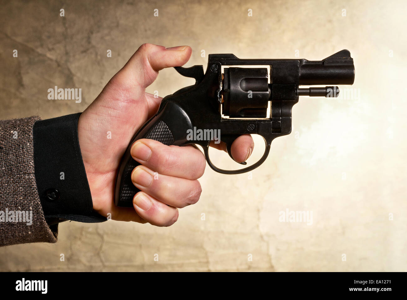 Silhouette of a mans hand with a handgun in brown Stock Photo