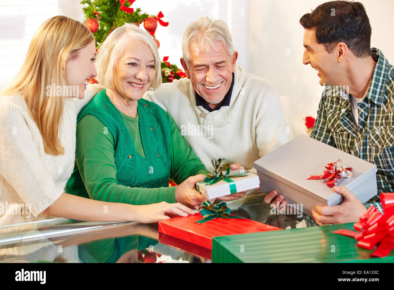 Happy senior citizens celebrating christmas with their children and gifts Stock Photo