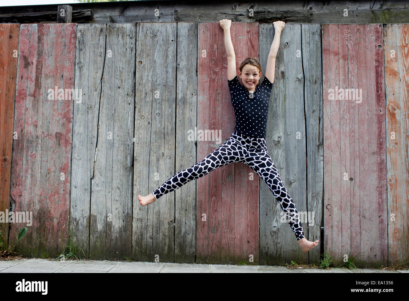 Teenage girl hanging from wooden fence Stock Photo