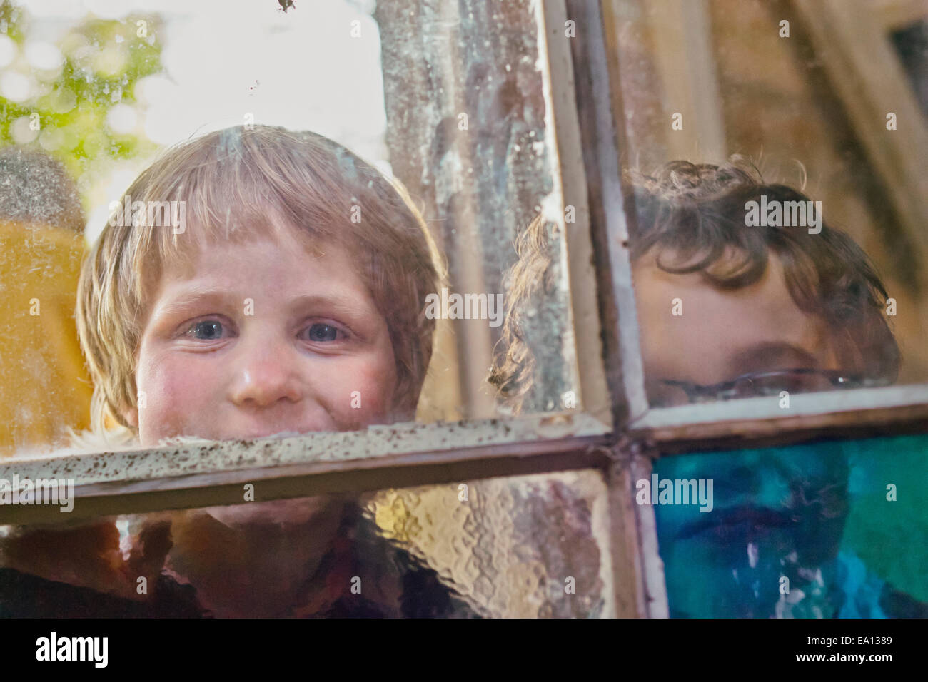 Portrait of two boys looking through hut window Stock Photo