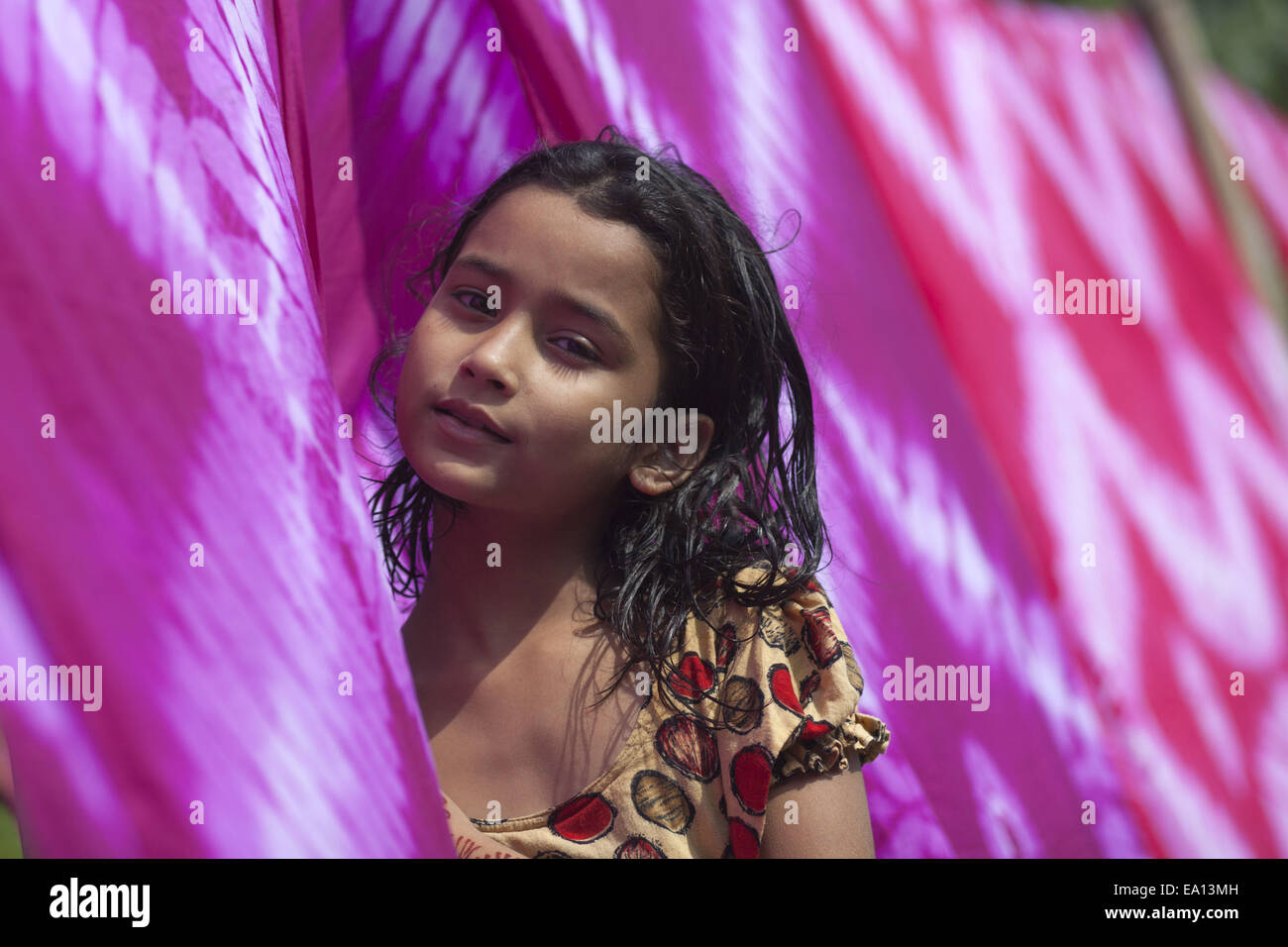 Narayangonj, Bangladesh. 5th Nov, 2014. A girl drying dyed cloths under sun, she is contributing to her family business.Village people in Bangladesh doing hand dyed clothing business.Taking small loan they collect raw cloths from factory, after dyed they dried them under sun and then sell them in market and they are stable now. © Zakir Hossain Chowdhury/ZUMA Wire/Alamy Live News Stock Photo