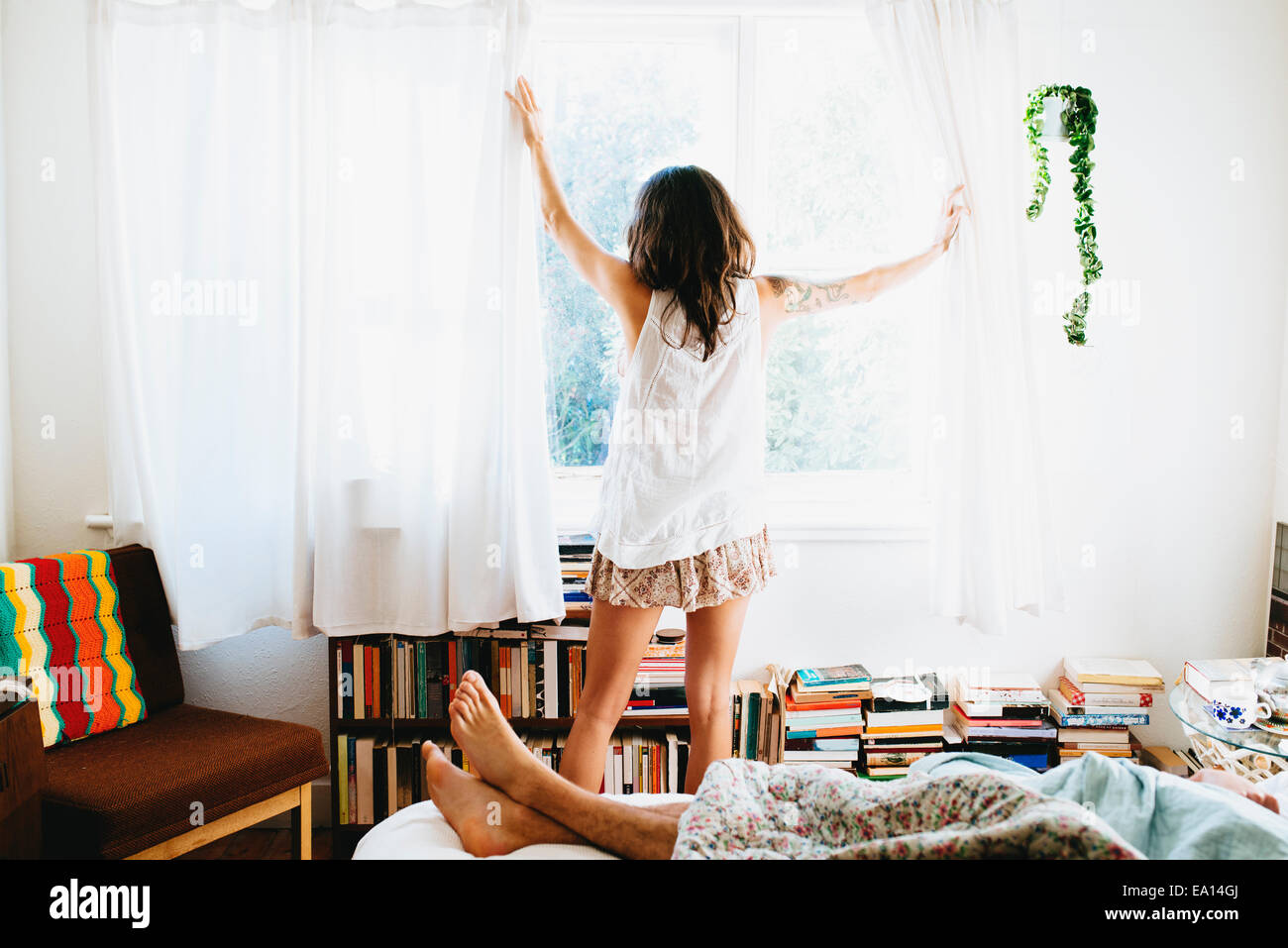 Woman drawing curtains open Stock Photo