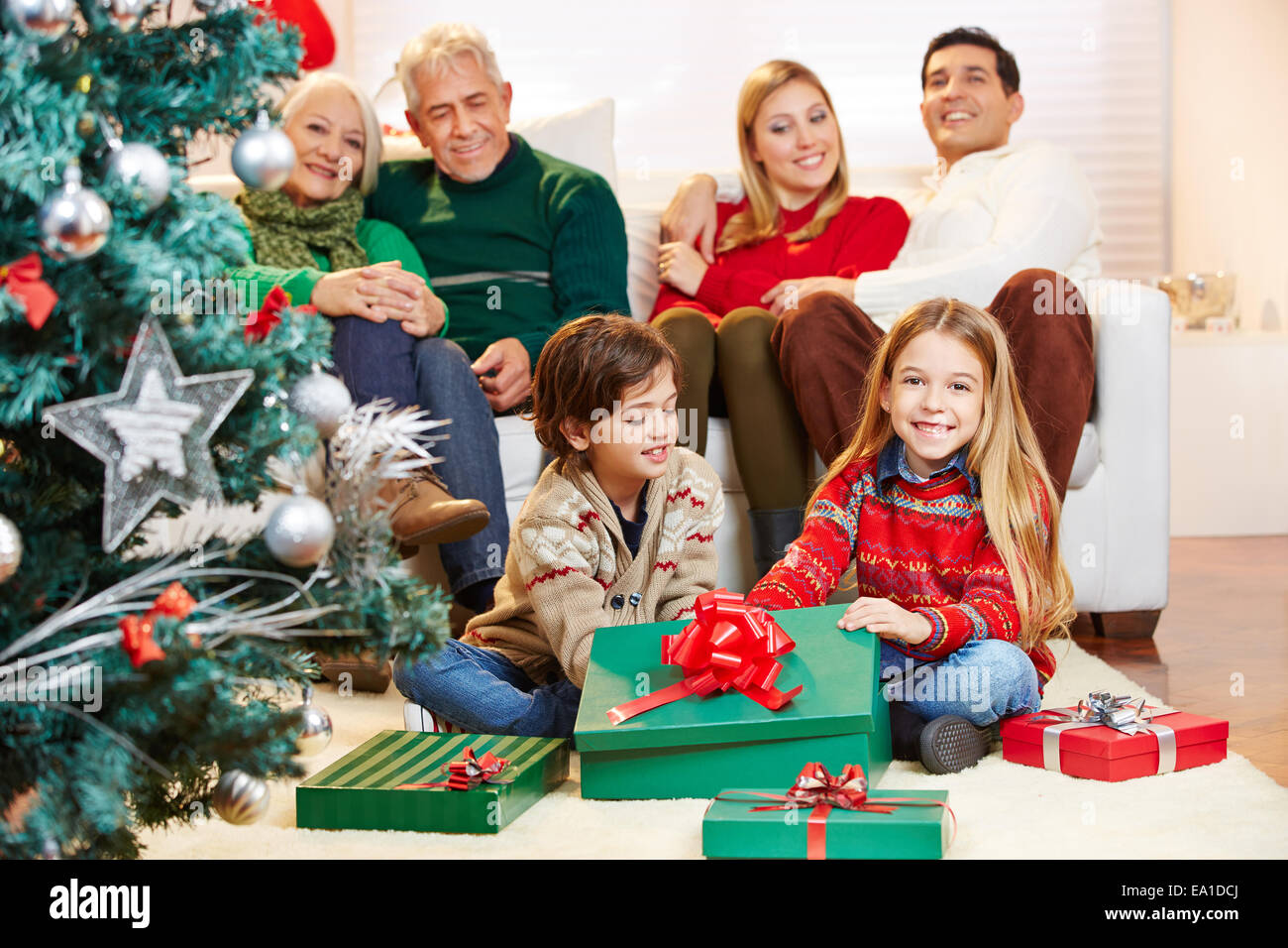 Chrildren making gift giving at christmas eve with family Stock Photo Giving At Christmas