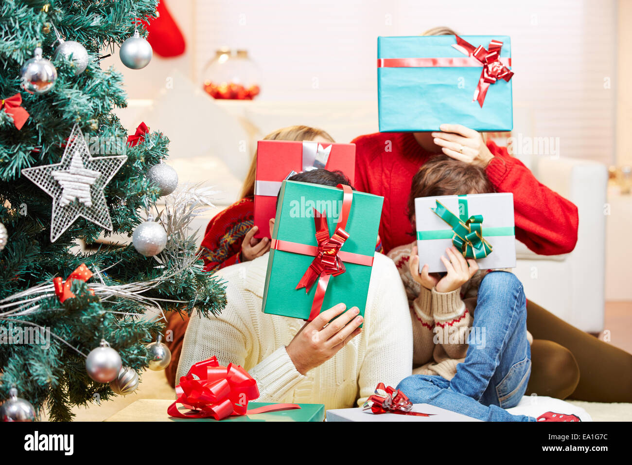 Happy family holding gifts in front of their faces at christmas Stock Photo