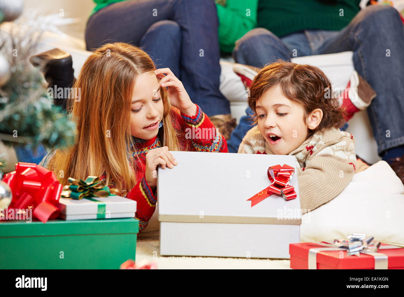 Two happy children opening gifts together at christmas eve Stock Photo