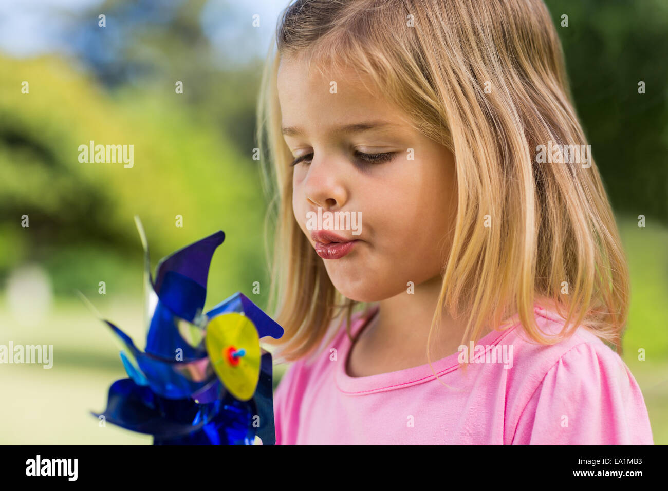 Cute girl blowing pinwheel at park Stock Photo Alamy