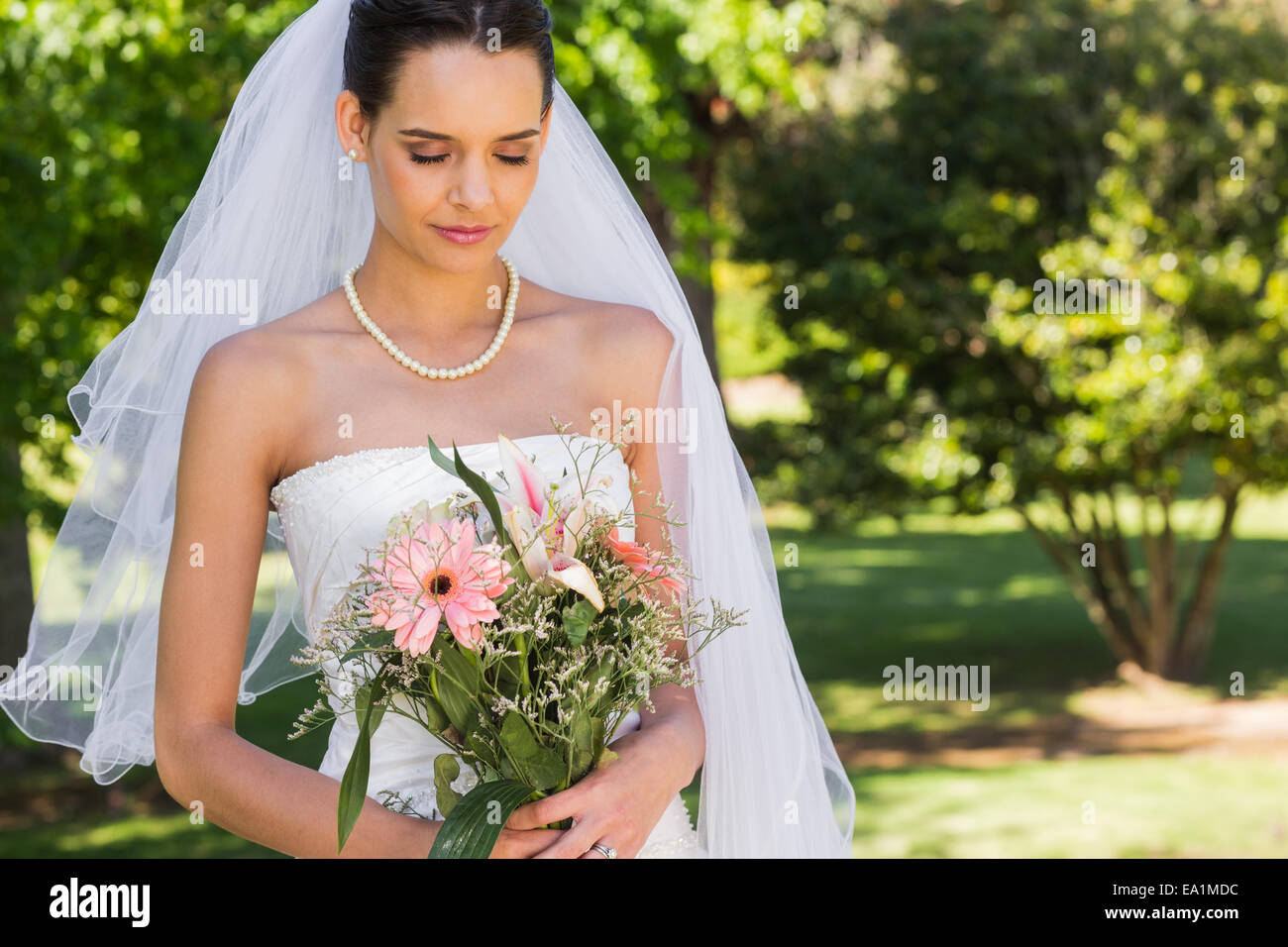 Serious beautiful bride with bouquet in park Stock Photo - Alamy