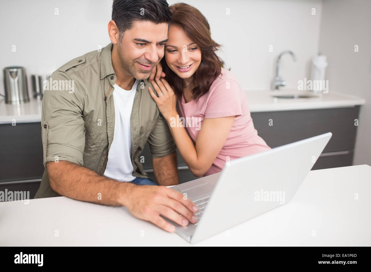 Happy couple using laptop in kitchen Stock Photo - Alamy