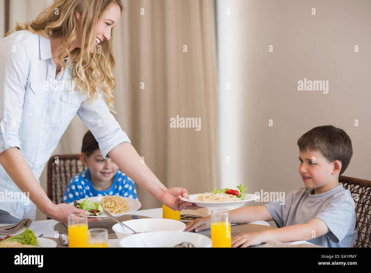 Mother serving pasta to son at dining table Stock Photo - Alamy