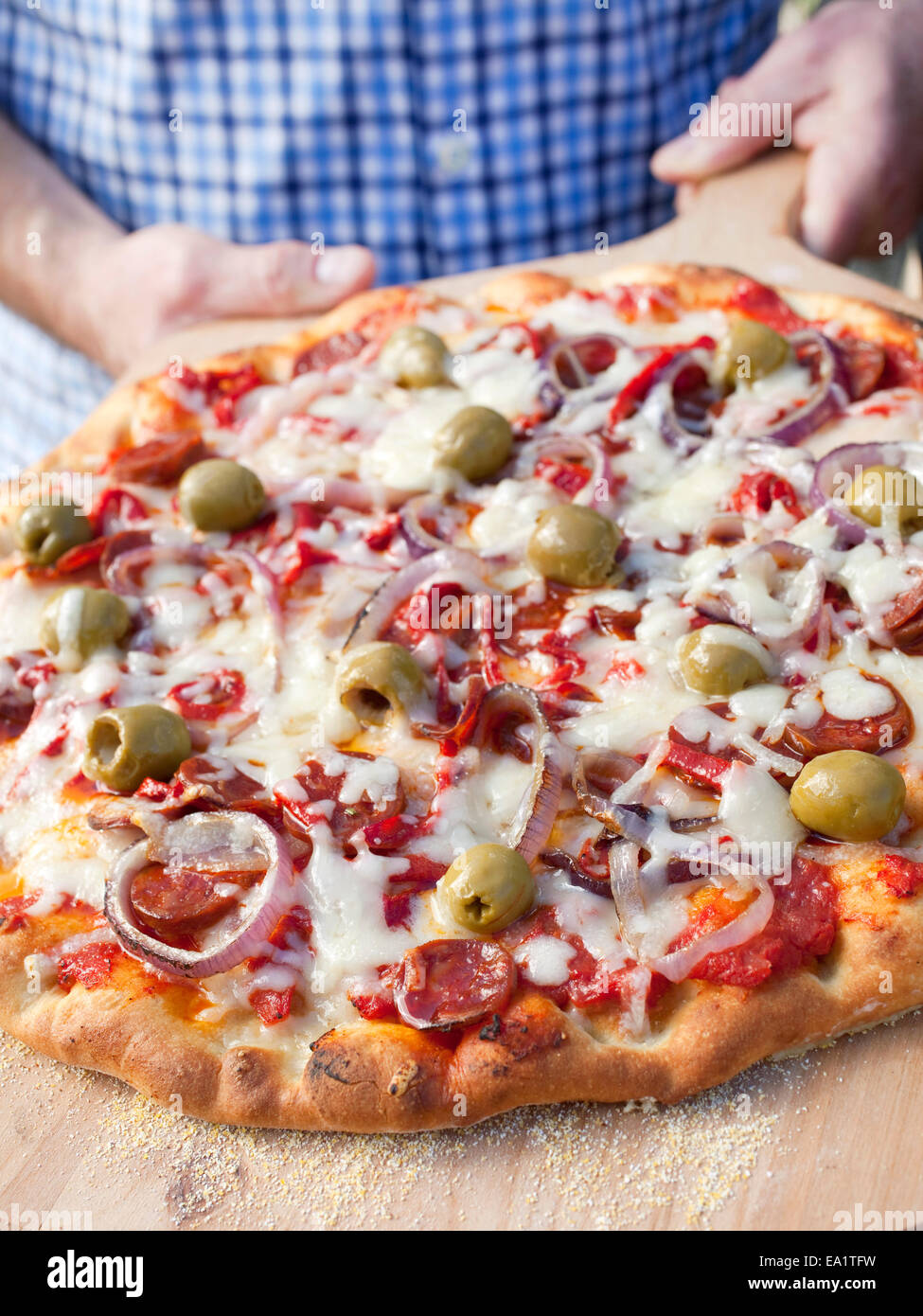 a grilled pizza with olives and onions on cutting board Stock Photo
